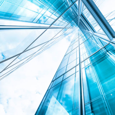 Looking up at a tall glass building toward blue sky